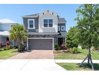 Inviting two-story home featuring a brick driveway, stone accents, gray painted facade, and well-manicured landscaping at 2815 Dudley Ave, Odessa, FL 33556