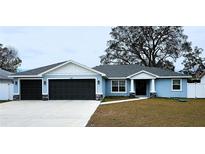 Charming home with a two-car garage, light-blue siding, dark roof, and well-manicured lawn at 9089 Dupont Ave, Spring Hill, FL 34608