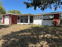 A single story home features a brick accent, a white door garage, and screen porch at 9104 Lido Ln, Port Richey, FL 34668