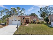 Charming single-story home with well-manicured lawn, brick accents, and a welcoming red front door at 9652 Oakwood Hills Ct, New Port Richey, FL 34655