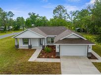 Beautifully landscaped single-story home featuring a neutral palette, and attached two-car garage at 12331 Fulmar Rd, Weeki Wachee, FL 34614