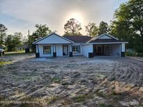 Charming single-story home featuring white exterior, dark trim, and a spacious front yard awaiting landscaping at 12331 Fulmar Rd, Weeki Wachee, FL 34614