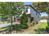 Two-story home features a front yard with lush landscaping, a paver driveway, and a cozy porch swing at 12889 Burns Dr, Odessa, FL 33556