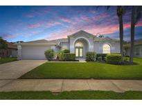 Charming single-story home with lush landscaping and a well-manicured lawn under a colorful sunset sky at 22118 Yachtclub Ter, Land O Lakes, FL 34639