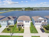 Beautiful aerial view of homes near a lake, featuring manicured lawns and scenic water views on a sunny day at 3208 Living Coral Dr, Odessa, FL 33556
