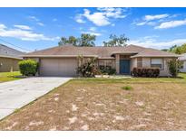 Charming single-story home featuring a well-manicured lawn, attached garage, and inviting blue front door at 4335 Duval St, Spring Hill, FL 34606