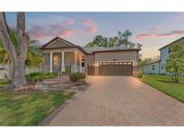 Charming single-Gathering home featuring a brick driveway, two-car garage, a cozy porch, and manicured landscaping at 4910 Southern Valley Loop, Brooksville, FL 34601