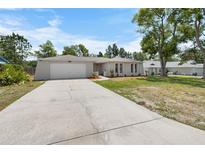 Charming single-story home featuring an attached garage and well-maintained front yard with mature landscaping at 5378 Mosquero Rd, Spring Hill, FL 34606