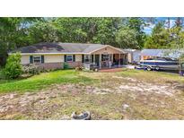 Charming one-story home featuring a covered front porch and a well-maintained lawn with mature trees at 6203 Sumter Dr, Brooksville, FL 34602