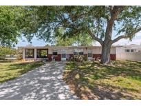 Charming single-story home with a brick facade, screened in porch, and a spacious front yard with mature trees at 6521 Boatyard Dr, Hudson, FL 34667