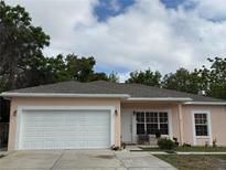 Charming single-story home featuring an attached garage, well-maintained lawn, and front door seating area at 7144 Gulf Breeze Cir, Hudson, FL 34667