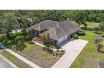 Well-maintained single-story home featuring brick accents, a two-car garage, and a landscaped front yard at 888 Royal Birkdale Dr, Tarpon Springs, FL 34688