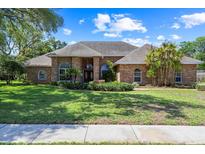 Charming brick home featuring manicured lawn and mature trees, perfect for curb appeal at 888 Royal Birkdale Dr, Tarpon Springs, FL 34688