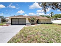 Charming single-story home with a neutral color scheme, well-maintained lawn, and an attached two-car garage at 9088 Gallup Cir, Spring Hill, FL 34608