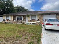 Charming single Gathering house featuring a stone facade, lovely landscaping, and attached garage at 1127 Lodge Cir, Spring Hill, FL 34606