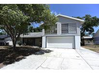 Two story home with an attached two car garage, mature trees, and a concrete driveway at 12210 Quail Run Row, Hudson, FL 34667