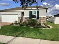 Charming single-Gathering home features manicured lawn, stone accents, and a two-car garage at 12630 Aston Dr, Hudson, FL 34669