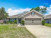 Charming single Gathering home showcasing a well-maintained lawn, mature landscaping, and an attached two car garage at 13111 Precept Way, Hudson, FL 34669