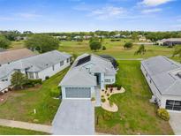 A light blue single-story home boasts a gray roof, two-car garage, manicured landscaping and backs up to a golf course at 18209 Breland Dr, Hudson, FL 34667