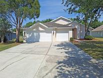 Attractive single-story home featuring a three-car garage, manicured lawn, and mature shade trees at 19855 Ellendale Dr, Land O Lakes, FL 34638