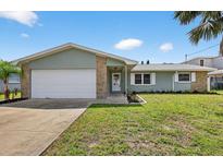 Charming single Gathering home with neutral siding, stone accents, manicured lawn, and a two-car garage at 2175 Edythe Dr, Dunedin, FL 34698