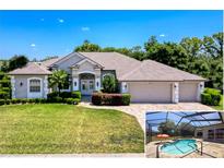 Beautiful single-story home with a three-car garage, lush landscaping, and a screened-in pool area at 3464 Misty View Dr, Spring Hill, FL 34609
