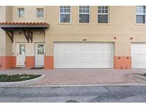 Tan two-story townhouse with a white garage door and nicely landscaped front at 658 Siren Wind Ln, Clearwater, FL 33756