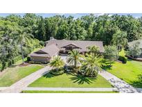 Expansive home with lush landscaping, mature palm trees, and paver driveway at 663 Turnberry Ct, Tarpon Springs, FL 34688