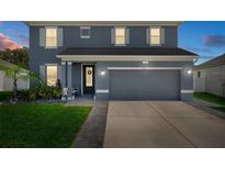 Charming two-story home with a well-manicured lawn, lush greenery, and a gray two-car garage at 733 Old Windsor Way, Spring Hill, FL 34609
