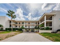 A condo building with balconies and a covered drive-through showcases tropical landscaping and a bright, sunny ambiance at 8210 Aquila St # 218, Port Richey, FL 34668