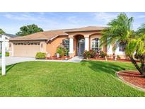 Charming single Gathering home featuring a well-manicured lawn, arched entryway, and attached two-car garage at 12040 Penzance Ln, New Port Richey, FL 34654