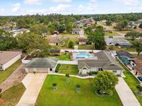 Aerial view of a property showcasing a backyard pool, well-manicured lawn, and a three-car garage at 13052 Drysdale St, Spring Hill, FL 34609