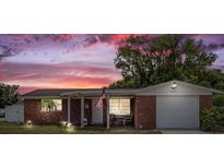 Charming single Gathering home with a brick facade and quaint front porch under a beautiful sunset at 3638 Bigelow Dr, Holiday, FL 34691