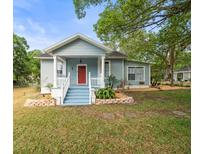 Charming single-Gathering home with a red front door, a quaint porch and vibrant landscaping at 606 Howell Ave, Brooksville, FL 34601