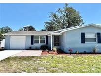 Charming single-story home showcasing blue siding, brick walkway and well-maintained landscaping at 9034 Cochise Ln, Port Richey, FL 34668