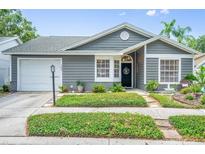 Charming one-story home with gray siding, manicured landscaping, and a cozy front porch at 1486 Loman Ct, Palm Harbor, FL 34683