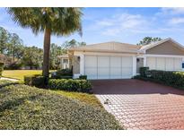 Charming home featuring a well-manicured lawn and a red brick driveway leading to a two-car garage at 15038 Sterling Run, Brooksville, FL 34609