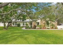 Charming single-story home with stone accents, mature trees, and lush landscaping on a spacious lot at 18633 Oak Way Dr, Hudson, FL 34667