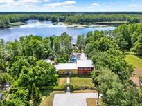 Stunning aerial view of a lakefront estate surrounded by lush greenery and a private dock at 4541 School Rd, Land O Lakes, FL 34638