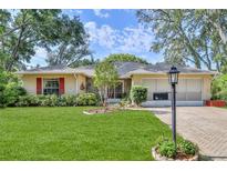 Charming single-story home with a well-manicured lawn, red shutters, and a paved driveway leading to the garage at 6172 Prestwick Ct, Spring Hill, FL 34606