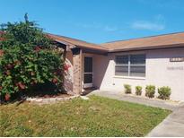 Single-story home featuring flowering bushes, stone accents, and a well-maintained lawn at 6205 Westport Dr, Port Richey, FL 34668