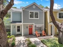 Charming multi-colored townhome with a bright red front door, two windows and chairs on a sunny day at 956 Franklin Ct, Palm Harbor, FL 34683