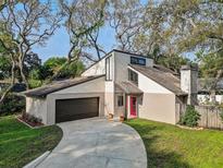 Charming two-story home with a unique architectural design, stucco siding, a red front door, and an attached two-car garage at 10910 Winter Oak Pl, Tampa, FL 33618