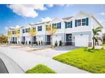 View of new townhomes with blue shutters, brick accents, well manicured lawn, and paver driveways at 12408 Amber Creek Cir, Lakewood Ranch, FL 34211