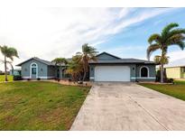 Charming single-story home with a well-manicured lawn and lush landscaping featuring palm trees at 305 Yellow Elder, Punta Gorda, FL 33955
