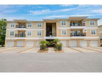Tan condos featuring balconies, individual garages, and palm tree landscaping, creating an inviting curb appeal at 5041 Royal Palms Way # 203, New Port Richey, FL 34652