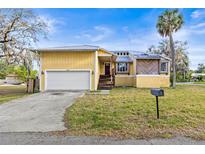 Inviting exterior of a yellow two-story home with a metal roof, attached garage, and a well-maintained front yard at 5422 Foley Sq, New Port Richey, FL 34652