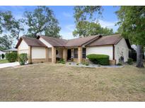 Charming one-story home featuring a well-maintained front yard and classic architectural details at 6490 Pine Meadows Dr, Spring Hill, FL 34606