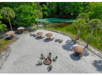Aerial view showcasing a sandy beach area with lounge chairs, fire pit and picnic tables, perfect for outdoor relaxation and entertainment at 6583 River Run Blvd # 21005, Weeki Wachee, FL 34607