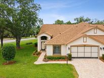 Charming home with a well manicured lawn, brick driveway, and mature trees under a clear blue sky at 8001 Summerbreeze Ter, Spring Hill, FL 34606